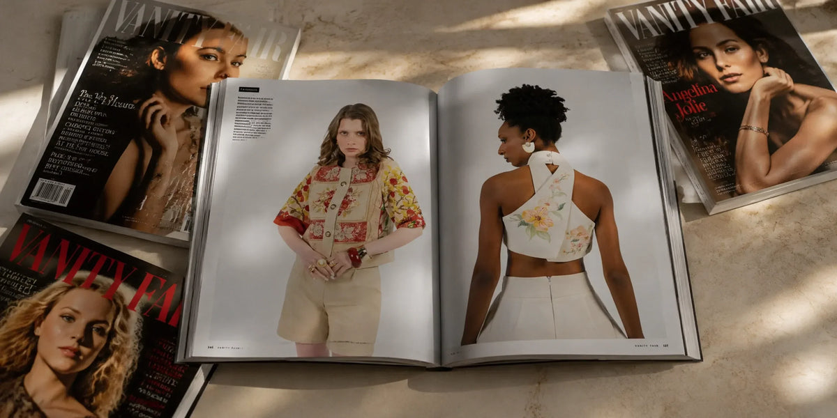 Open Vanity Fair magazine spread featuring models in Rondooz embroidered pieces, surrounded by other Vanity Fair covers on a marble surface with soft natural light
